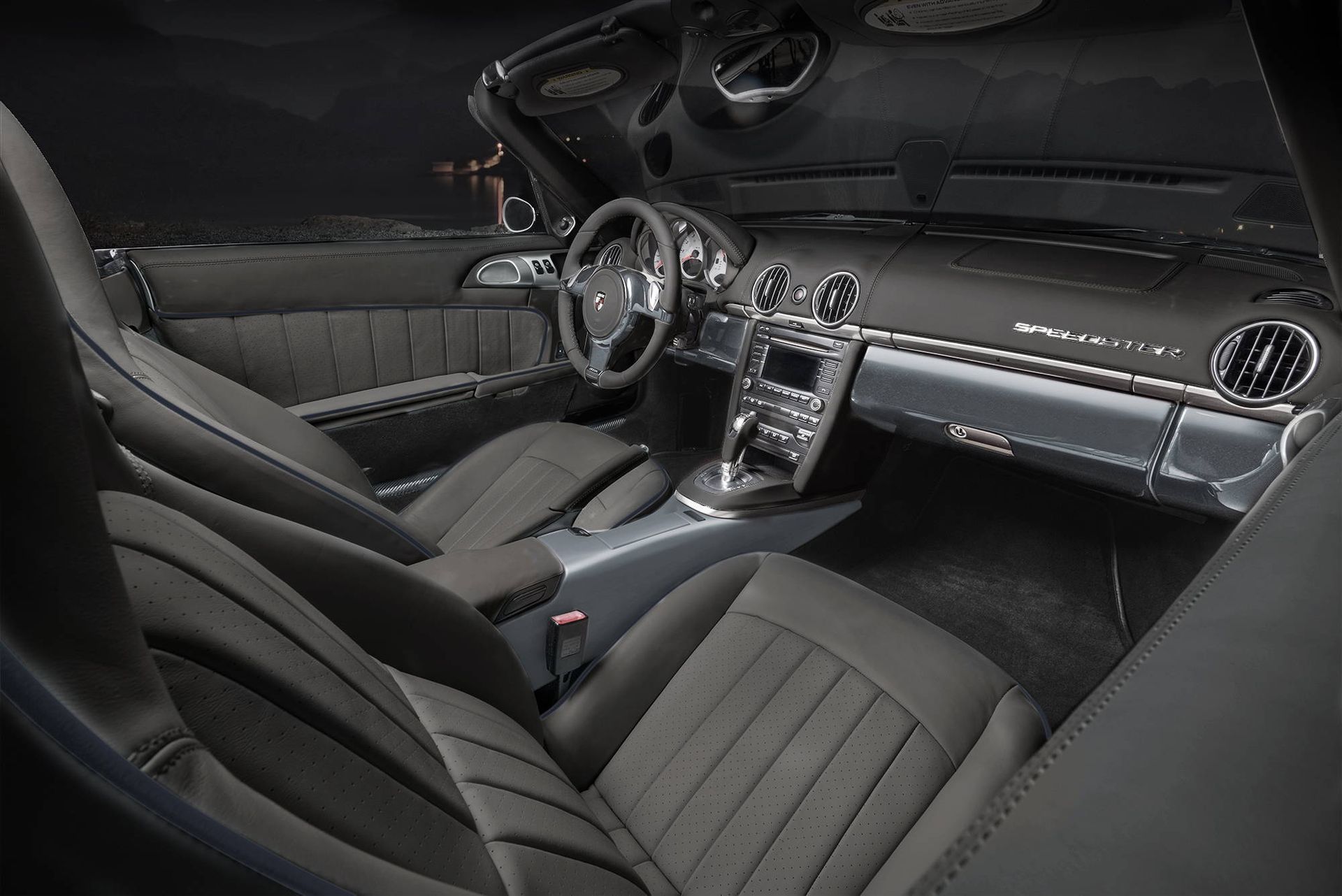 Luxury car interior with black leather seats, dashboard, steering wheel, and panoramic roof under night lighting