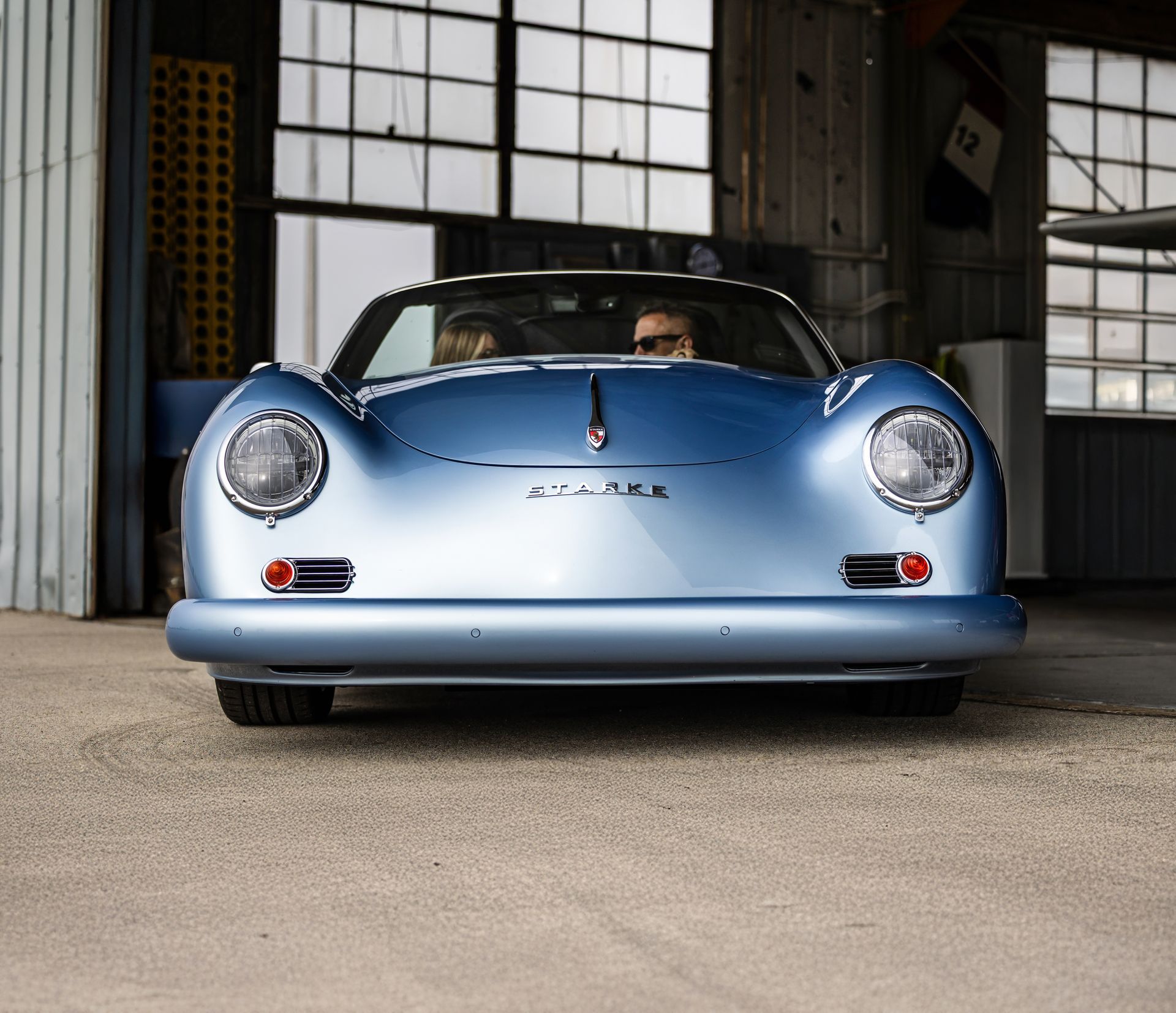 Light blue classic sports car parked in a garage, front view