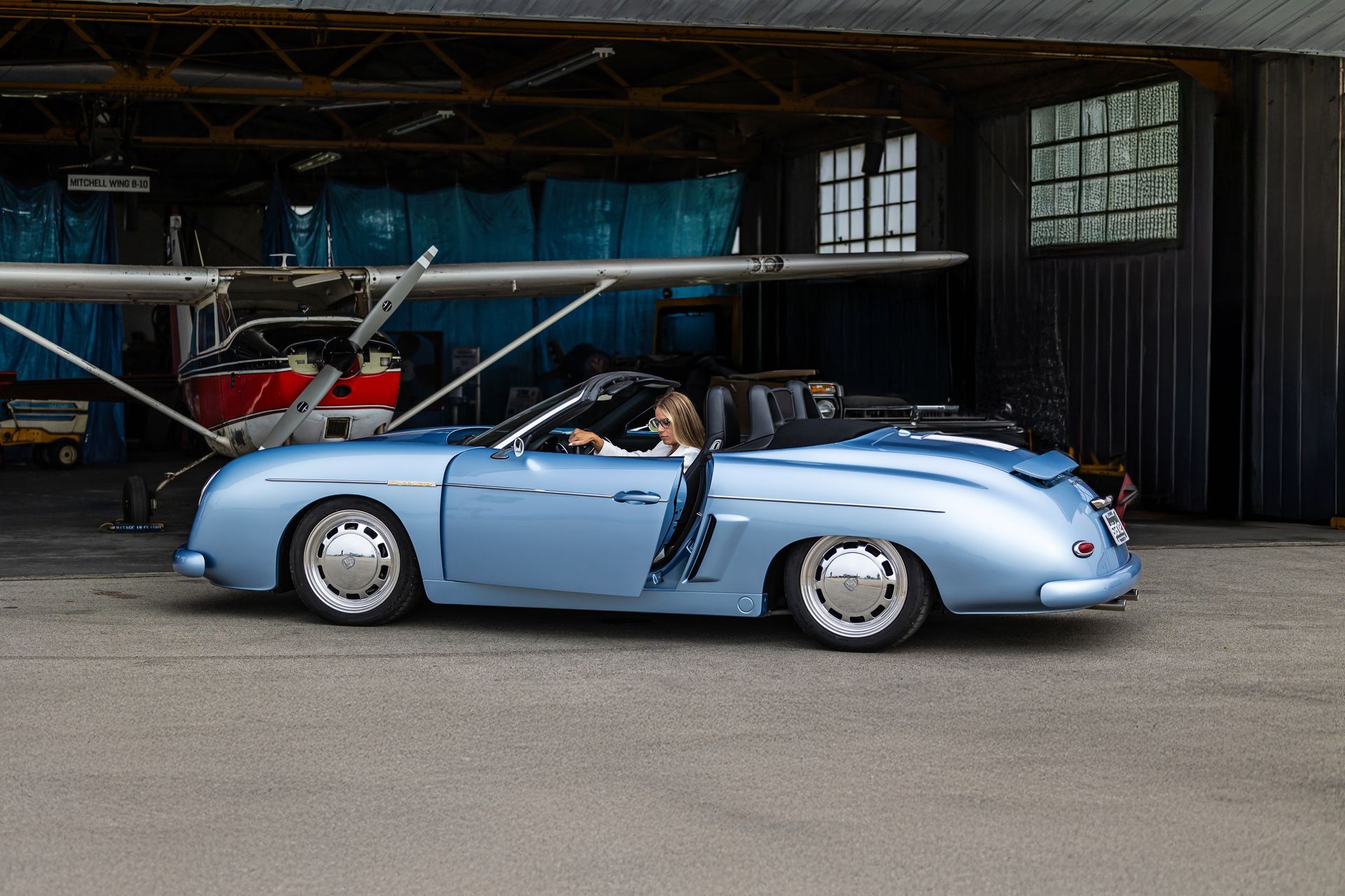 Light blue vintage convertible parked in a hangar with its top down