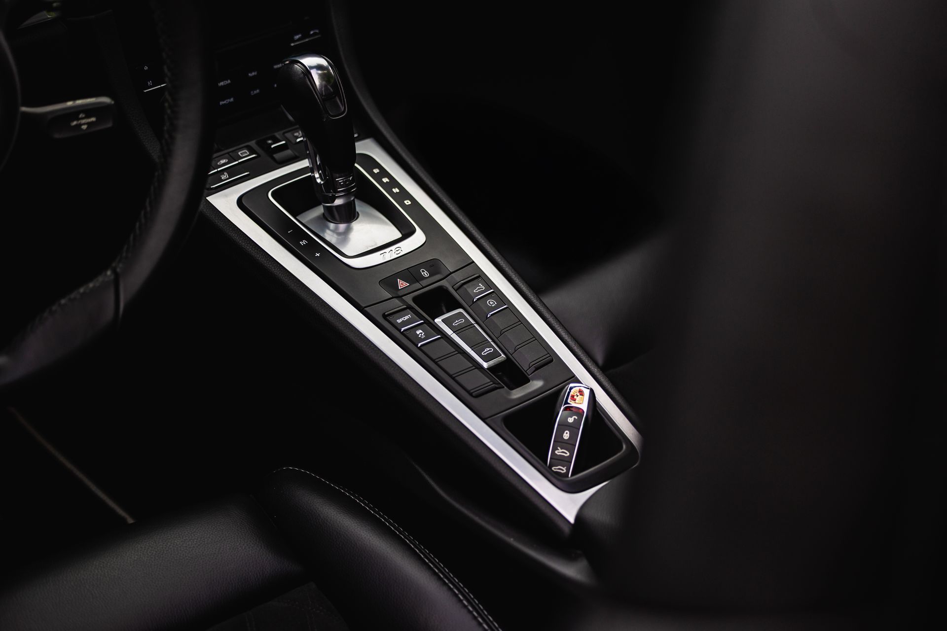 Luxury car center console with a gear selector and glossy black trim in a dark interior