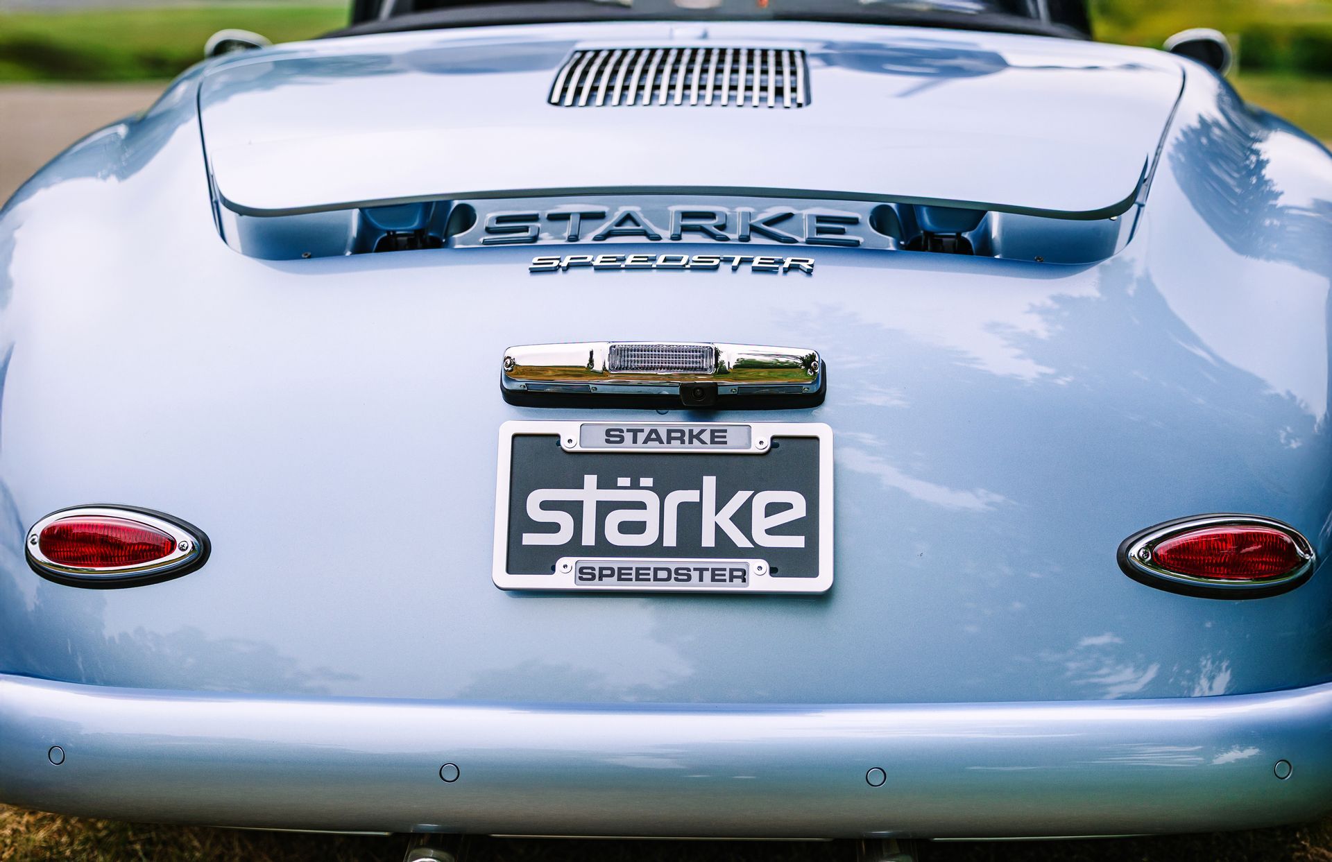 Rear view of a light blue classic car with STARKe branding and vintage badges.