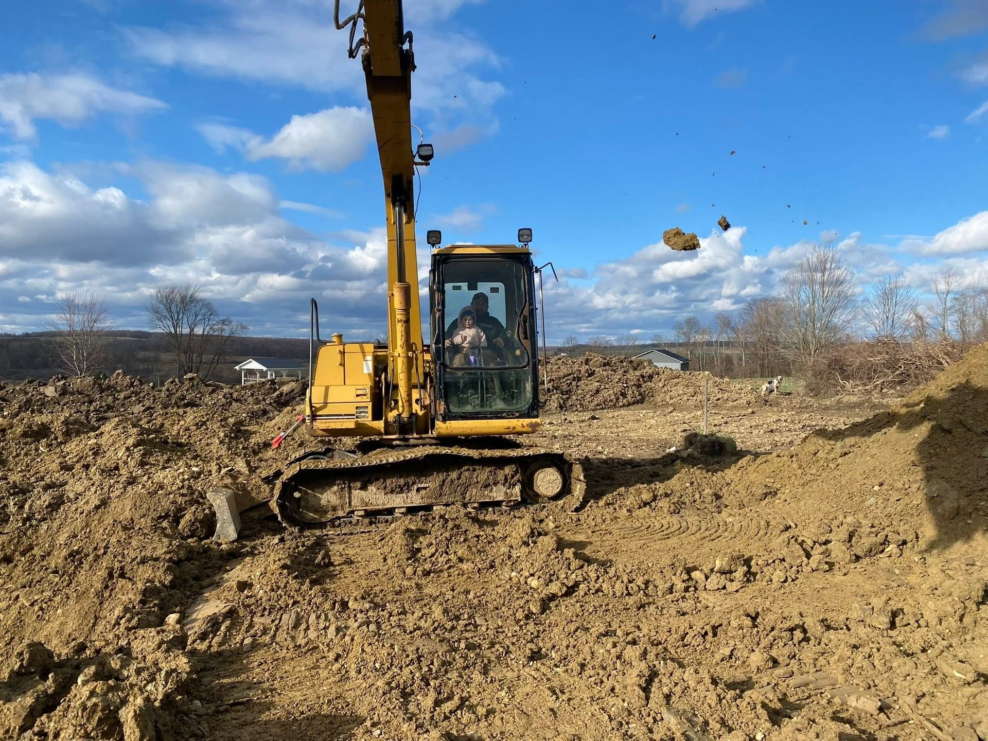 Yellow excavator on muddy construction site under a blue sky
