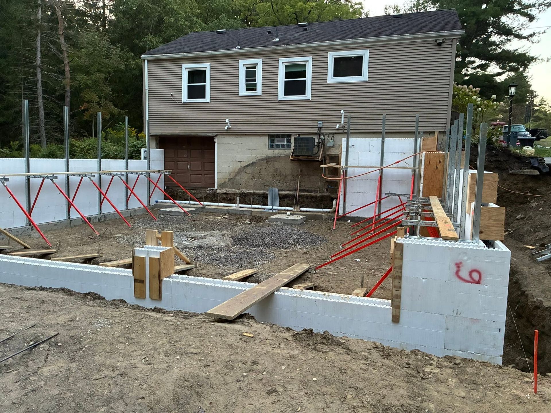 House under construction with concrete foundation and scaffolding in a wooded yard