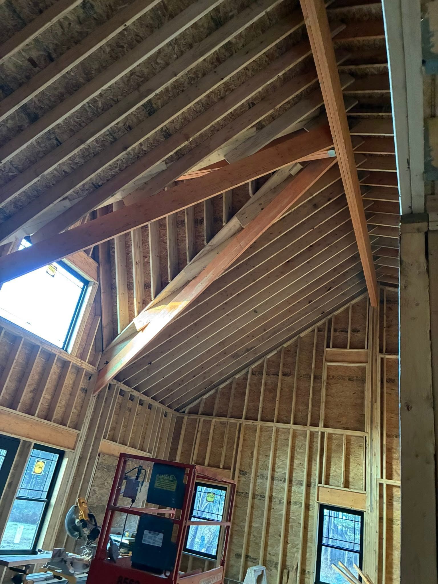 Interior of a wooden room with exposed vaulted roof beams and windows, viewed upward from below