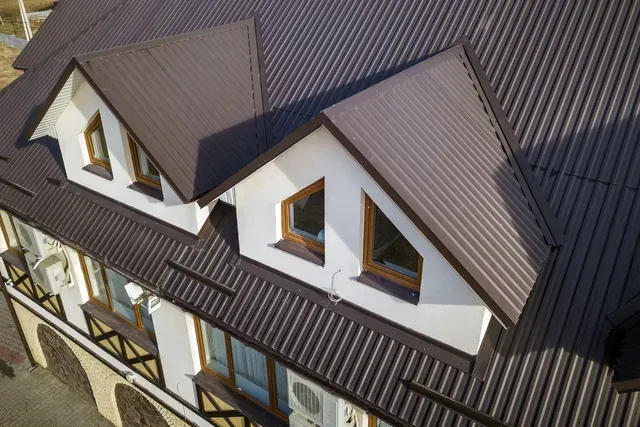 Brown corrugated metal roof on a building with white walls and dormer windows.