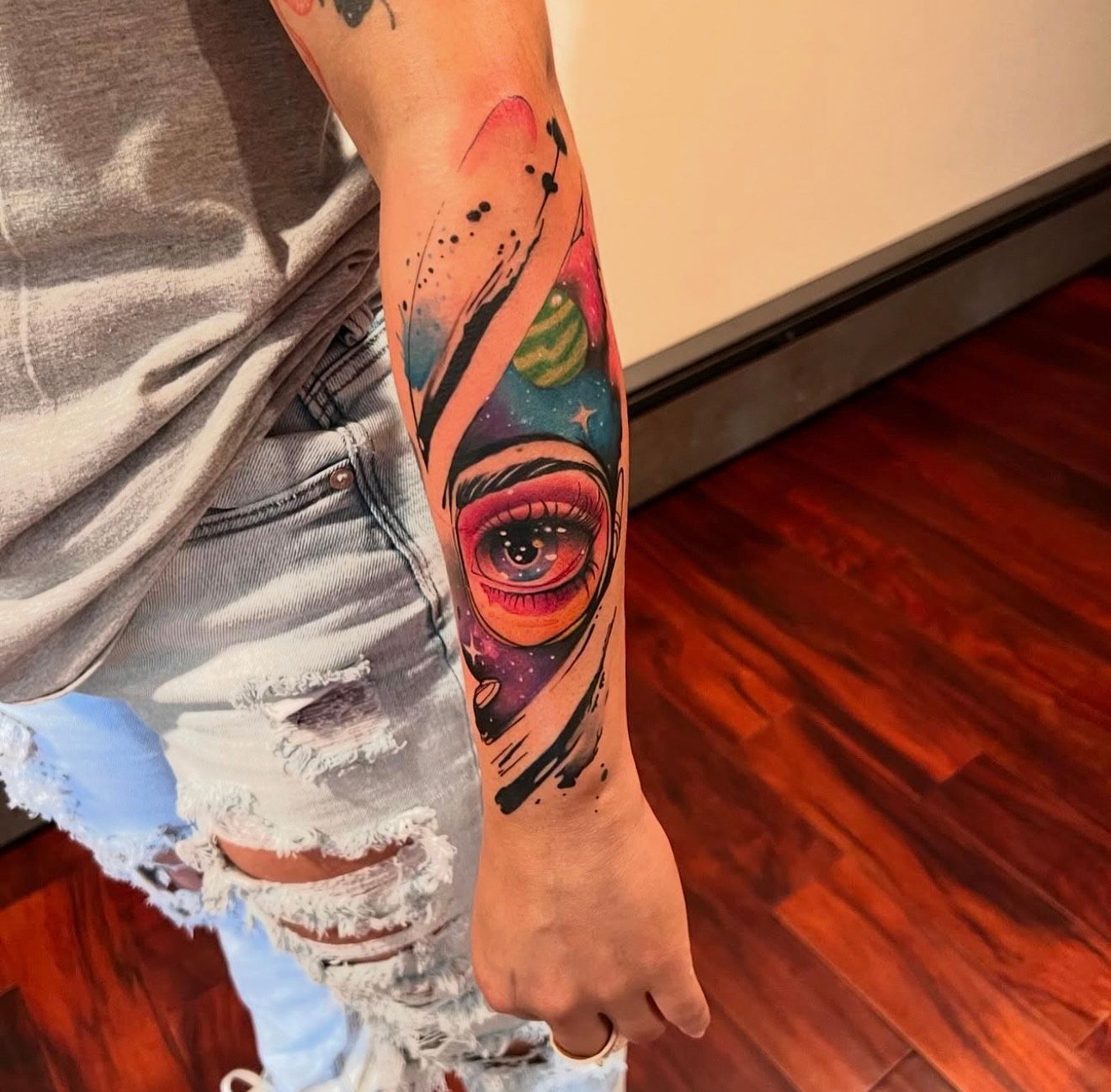 A woman has a colorful tattoo of an eye on her forearm