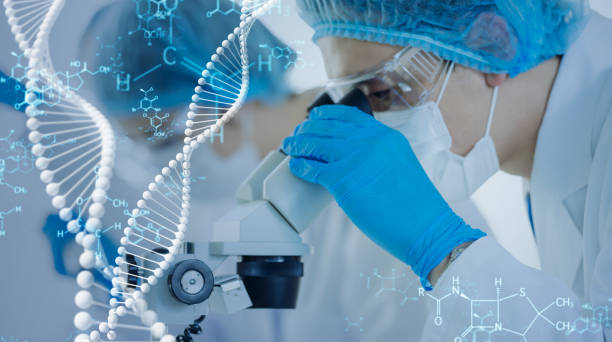 Scientist in blue gloves and mask examining a microscope in a lab, with DNA graphics overlayed