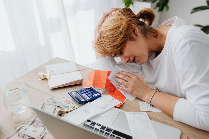 Person leaning over paperwork at a desk, studying a calculator and receipts while writing notes