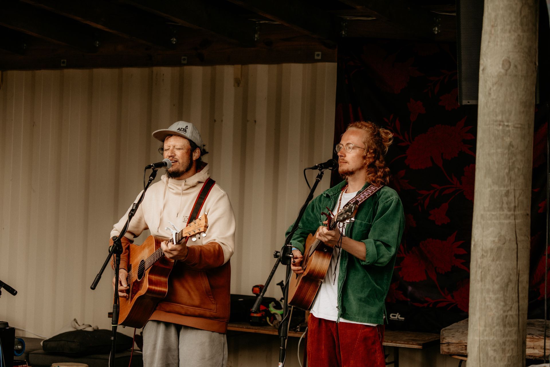 Two men playing acoustic guitars and singing on an outdoor stage.