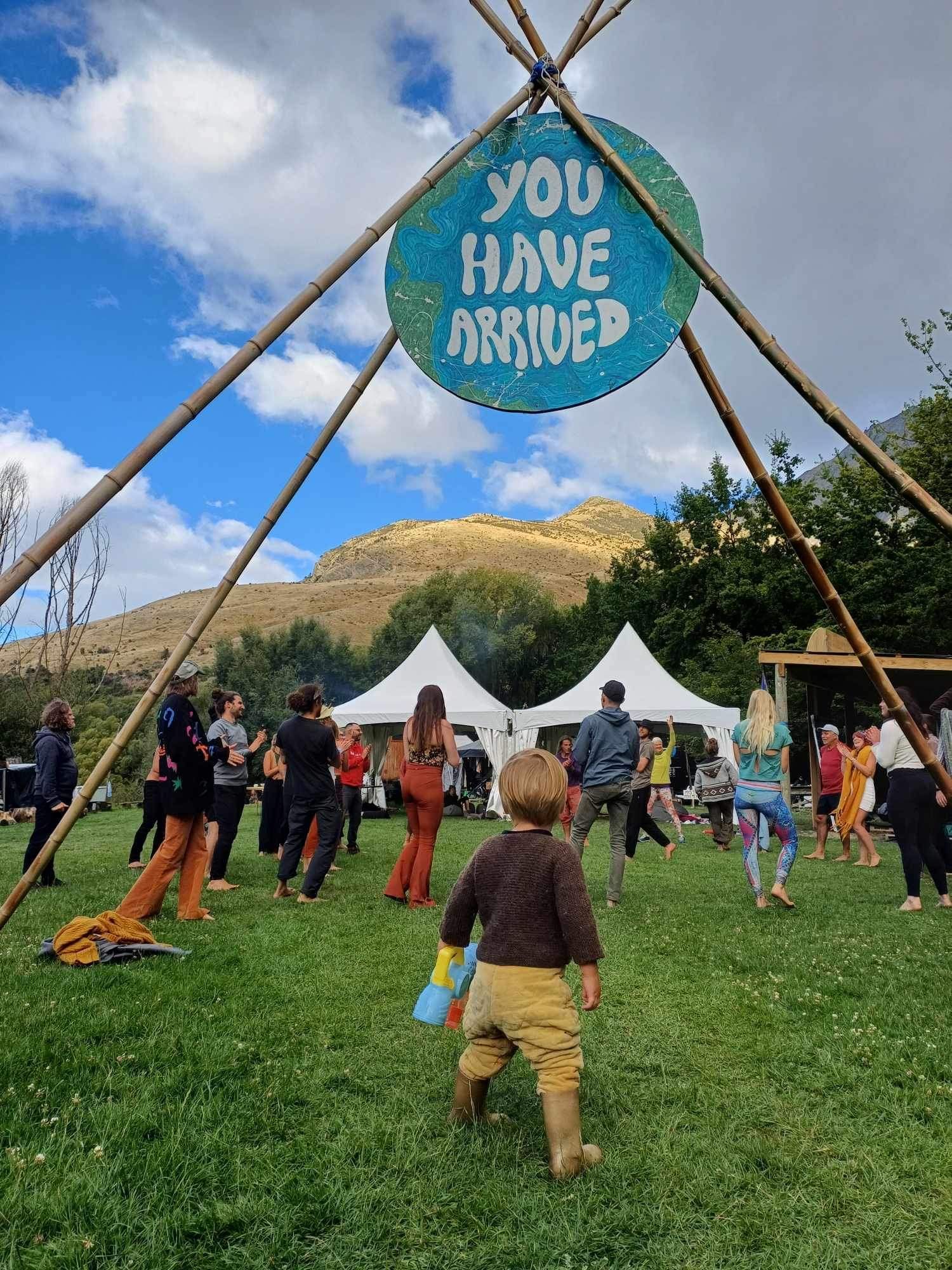 People at outdoor event under sign that reads 