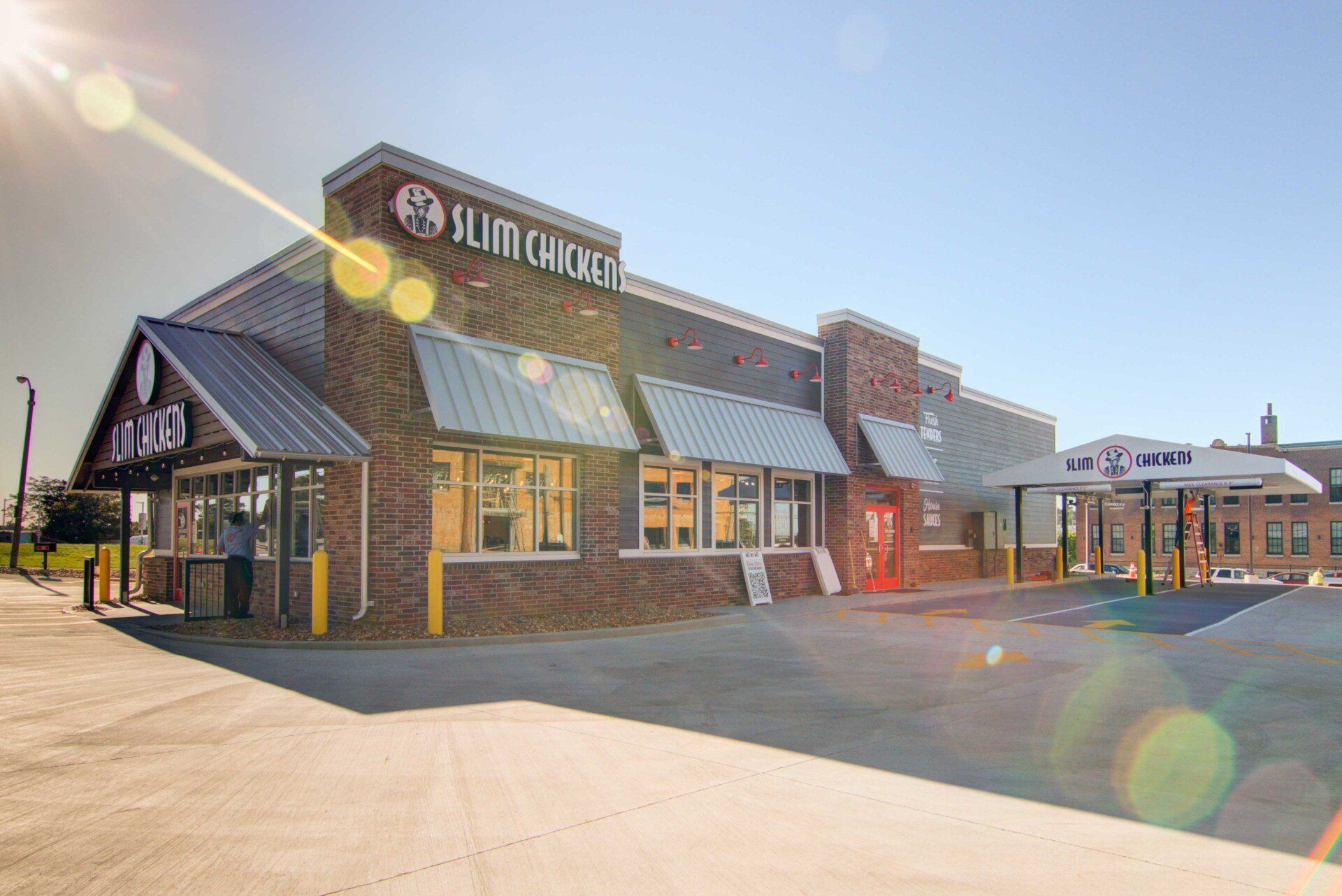 Slim Chickens restaurant building exterior with brick and metal roof.
