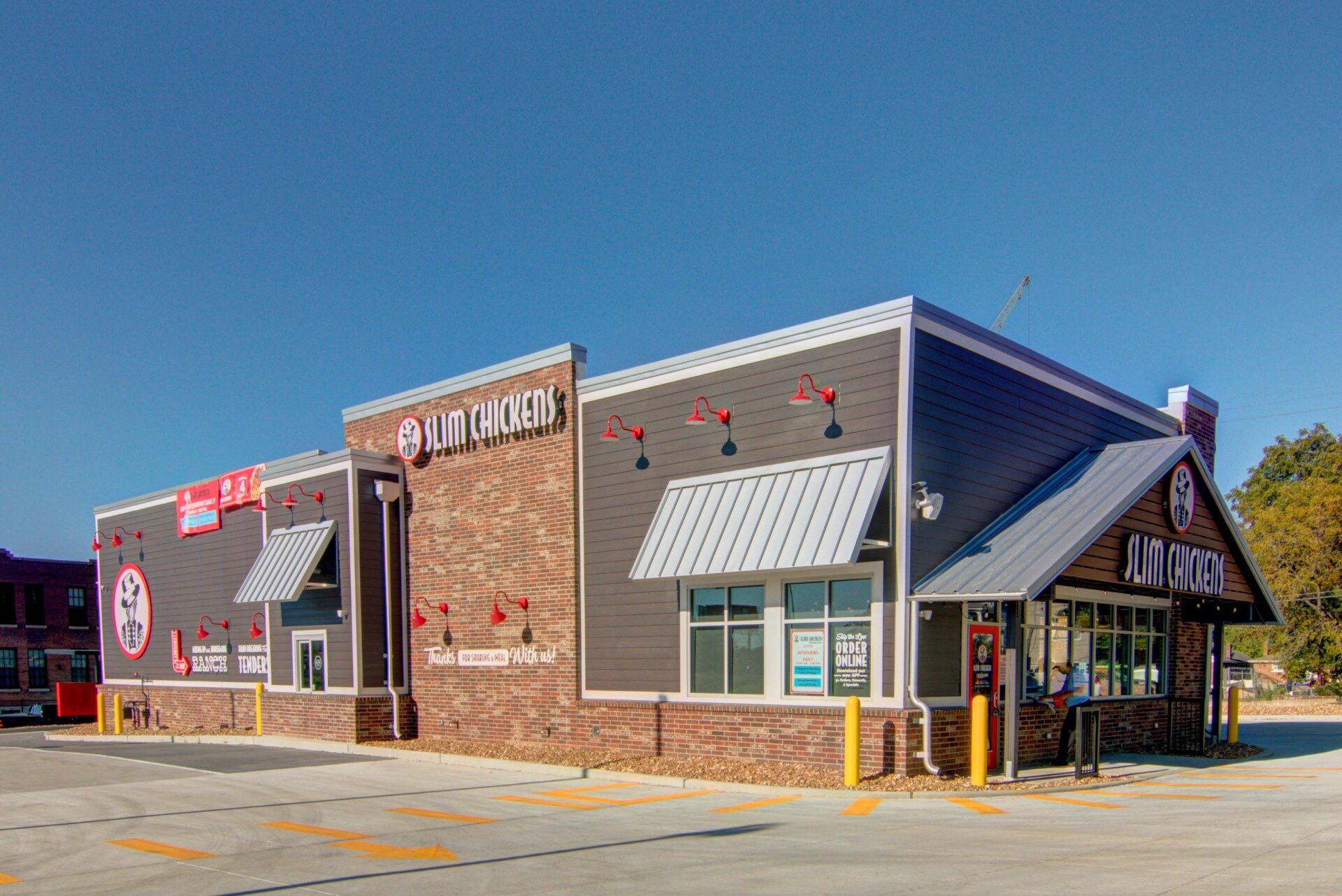 Restaurant exterior, gray and brick building with drive-thru, under clear blue sky.