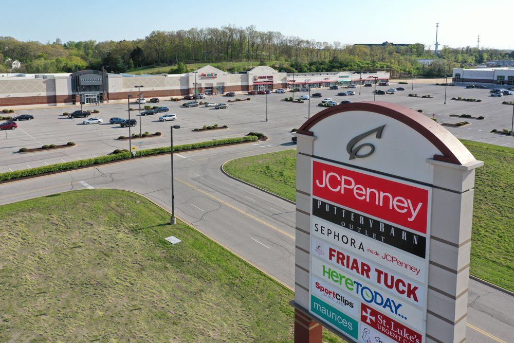Shopping center sign with JCPenney, Sephora, and other stores; outdoor setting, sunny day.