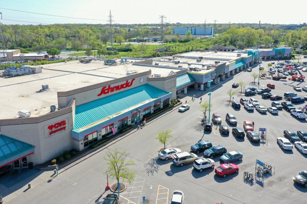 Aerial view of a shopping center with Schnucks supermarket and a parking lot filled with cars.