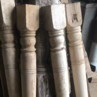 Wooden chair legs and spindles lined up in a workshop, unfinished and worn.