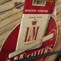 Red vintage L&M Filters cigarette pack with white cigarettes on a wooden surface