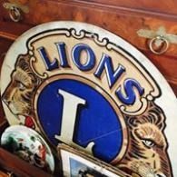 Lions club emblem with blue and gold lion crest on a wooden background