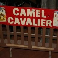 Red Camel Cavalier sign mounted on a wooden fence at night