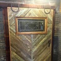 Rustic wooden door with small barred window and chevron plank pattern.