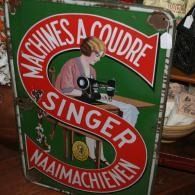 Vintage Singer sewing machine sign with red, green, and white lettering.