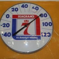Round Seagrams whiskey thermometer sign with red, white, and blue design on a yellow wall