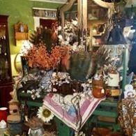 Colorful vintage shop display with flowers, lanterns, and decorative items on a table