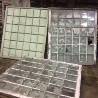 Three large glass window panes leaning against a wall, with one pane laid flat in front.