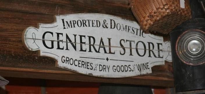 Vintage “General Store” sign hanging indoors, with “Groceries, Dry Goods, Wine” text