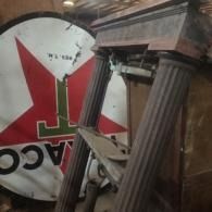Broken red and white sign with a Greek column lying in debris indoors
