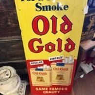 Yellow Old Gold cigarette display sign with red lettering and pack images on a store shelf