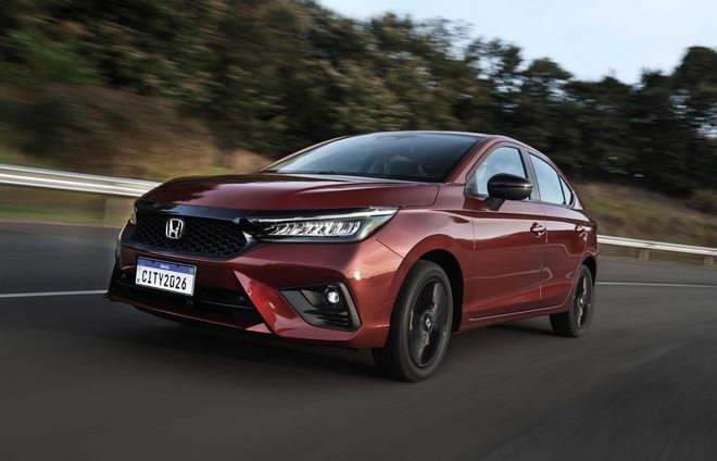 Sedan Honda vermelho dirigindo em uma rodovia.