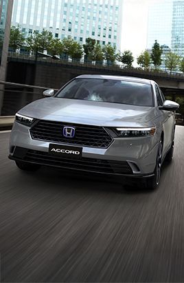 Sedan Honda Accord prata circulando em uma rua da cidade, com o logotipo "ACCORD" visível.