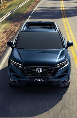 SUV Honda CR-V azul em uma estrada asfaltada, vista aérea. Grade preta, teto solar e emblema CR-V são visíveis.