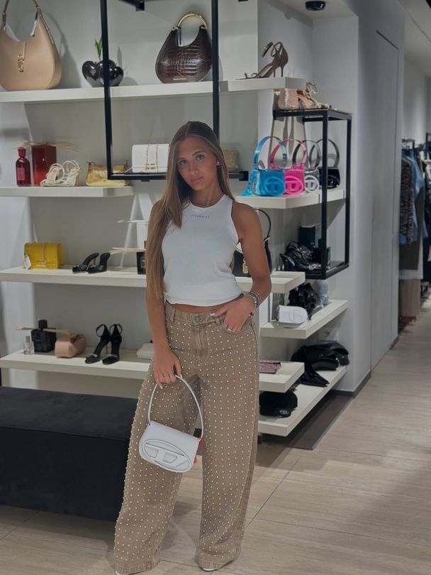 Piccola boutique di abbigliamento con scaffali pieni di vestiti colorati, un manichino e un bancone con la scritta 