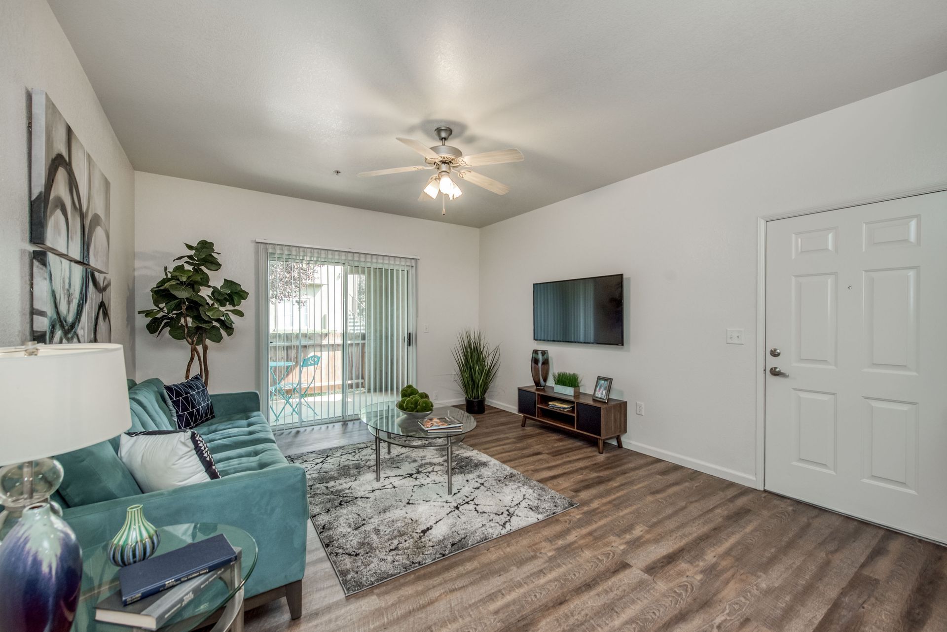a living room with a couch , television , and sliding glass doors .