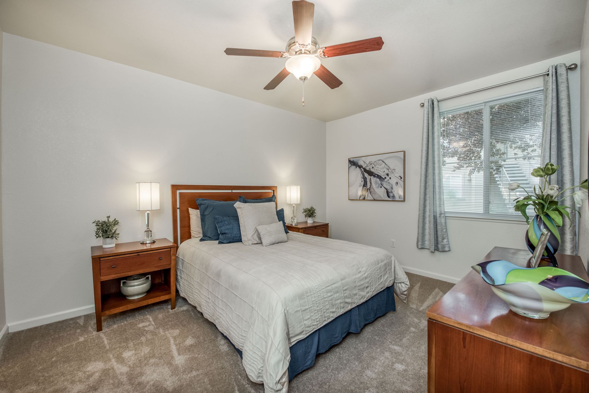a bedroom with a bed , nightstand , dresser and ceiling fan .