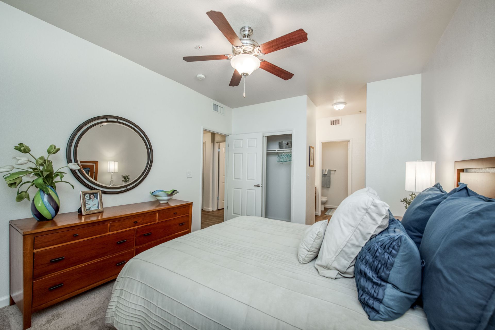 a bedroom with a bed , dresser , mirror and ceiling fan .
