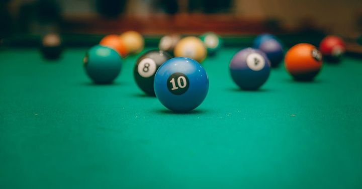 A pool table filled with pool balls and a blue ball with the number 10 on it.