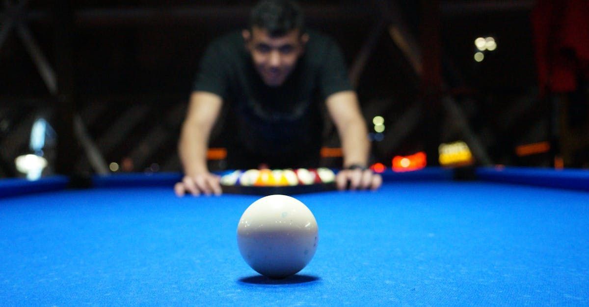 A man is playing pool on a blue pool table.