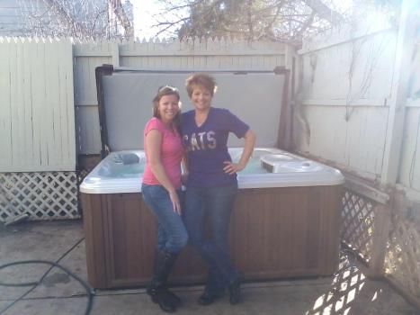 Two women standing next to a hot tub with one wearing a shirt that says cats