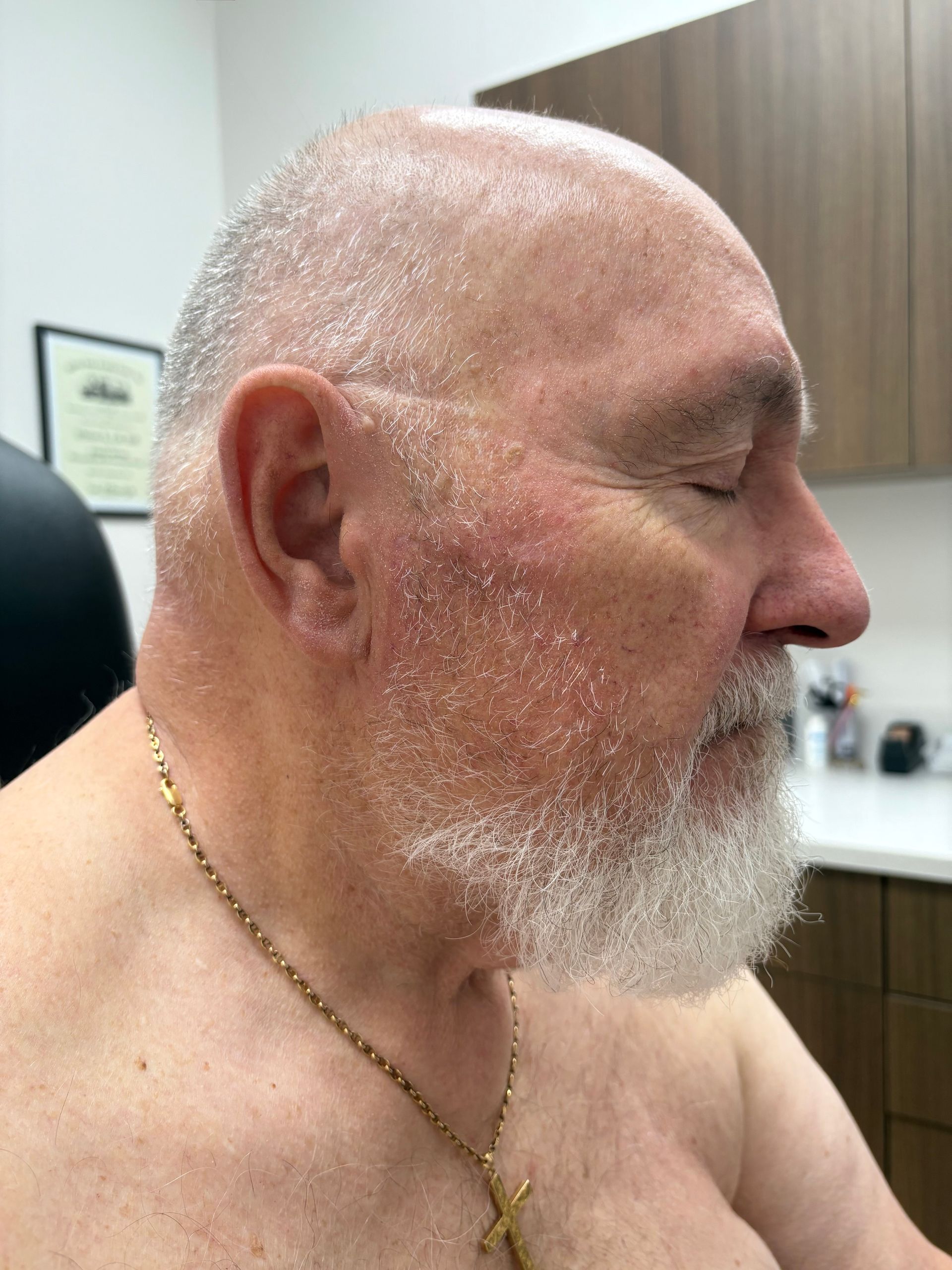 An older man with a beard and a gold chain around his neck.