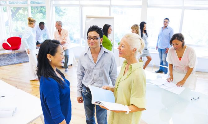 A group of people collaborating in a bright, modern office, with two people in the foreground discussing a document.