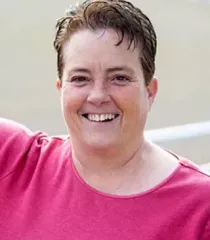 Smiling person in a bright pink shirt outdoors