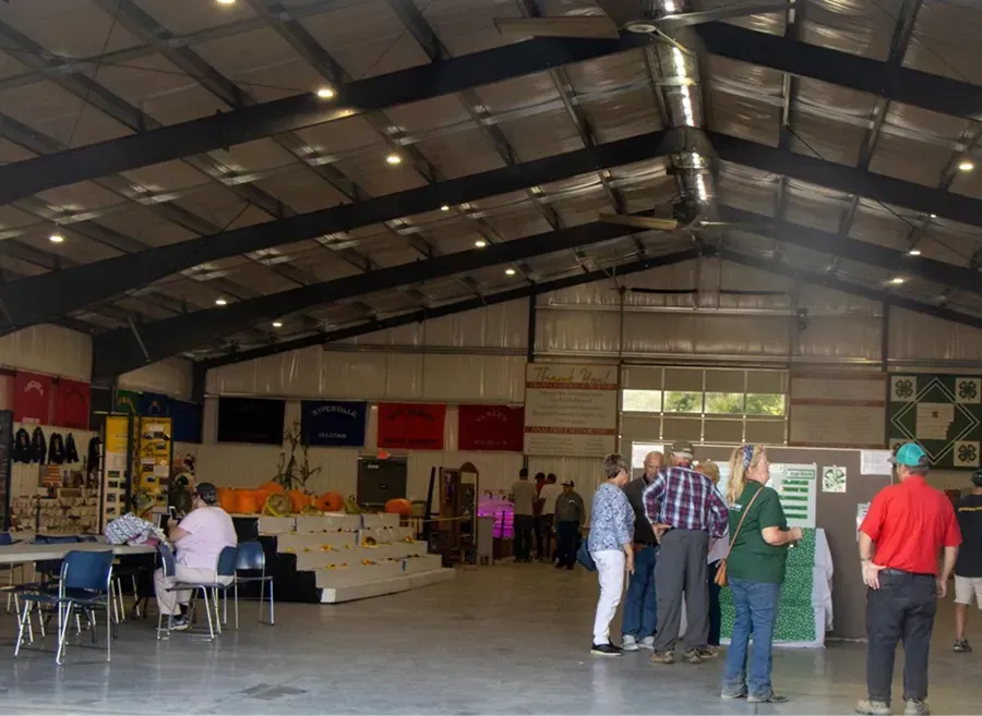 People mingling inside a large hall with rows of chairs and banners on the walls