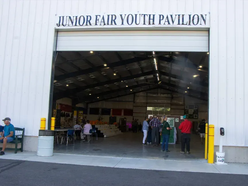 Entrance to the Junior Fair Youth Pavilion with people gathered inside a large open building