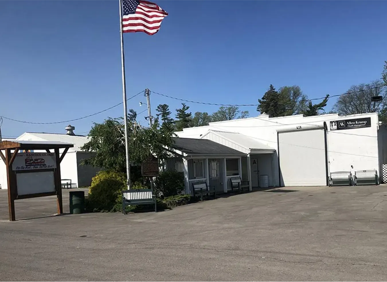 Small white building with an American flag flying in front, under a clear blue sky.