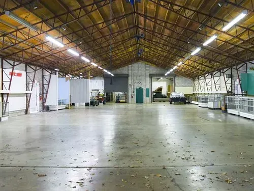 Empty industrial warehouse with a high metal roof and concrete floor
