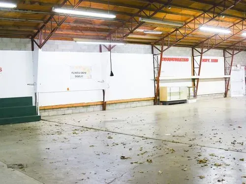 Empty warehouse with white walls, concrete floor, and exposed roof beams