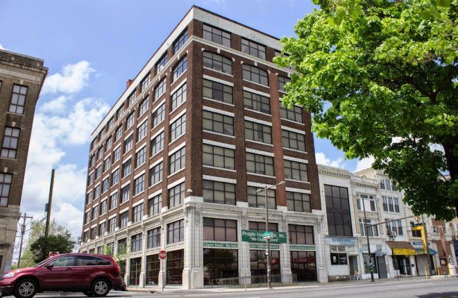 A red suv is parked in front of a large brick building