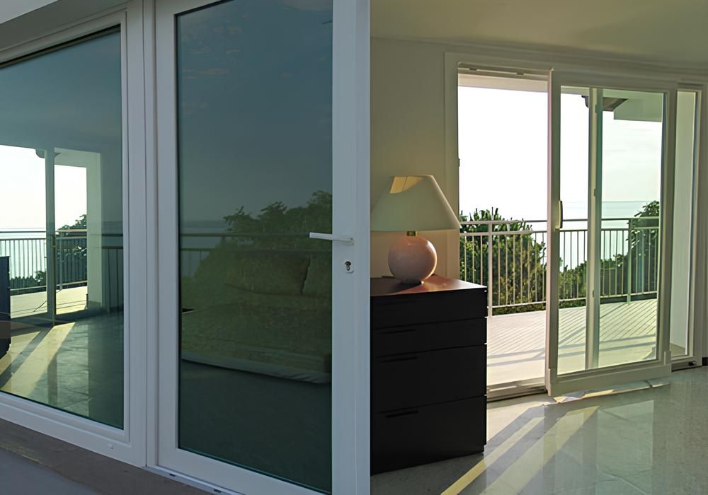 Le porte scorrevoli in vetro si aprono su un balcone con vista panoramica, accanto a una finestra con cornice bianca.